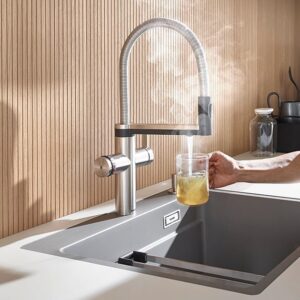 Moderner Kochendwasserhahn mit ausziehbarer Brause und Dampfentwicklung am Spülbecken